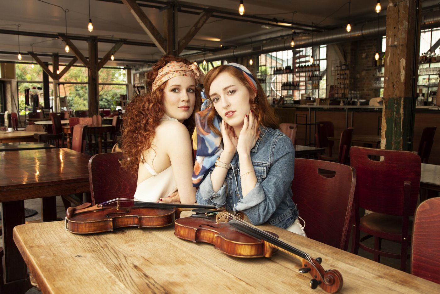 Camille et Julie Berthollet attablées, leurs violons posés devant elles